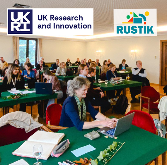 Photo of a room full of people working together at tables and laptops at a RUSTIK meeting with RUSTIK and UKRI logos superimposed on it.