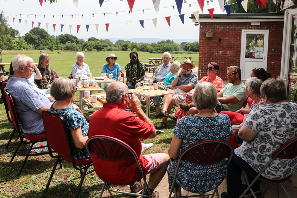 Judges and villagers chat at a tea party on the grass outside at Woolaston Memorial Hall