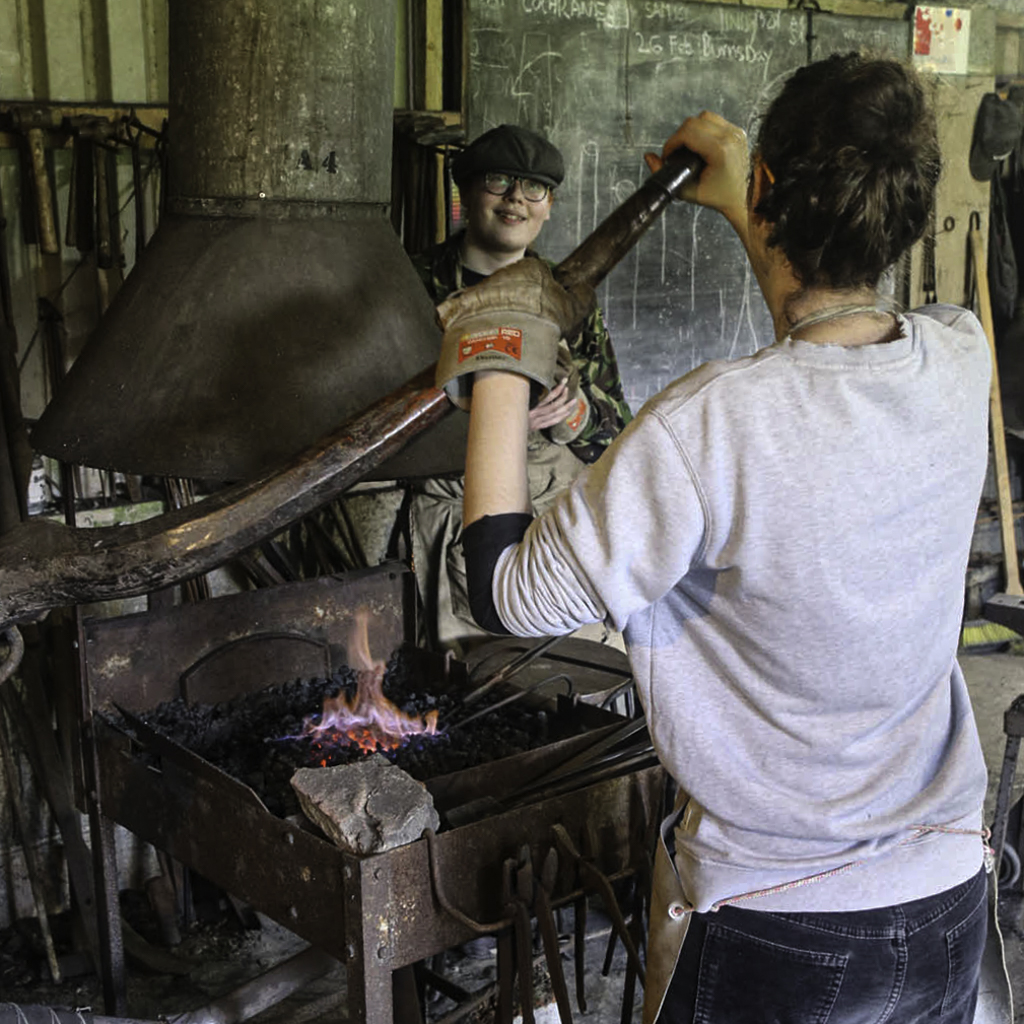 blacksmithing students working in the forge