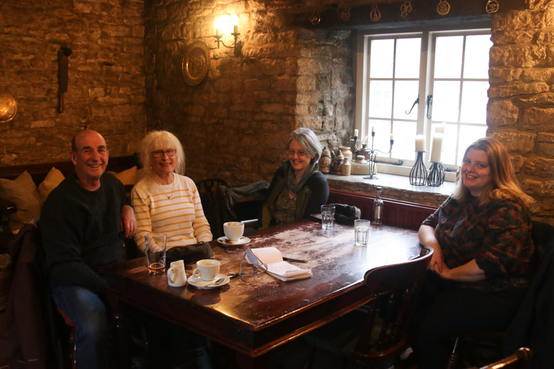 Four people sitting around a table in a darkly lit room in a pub in Frampton Mansell