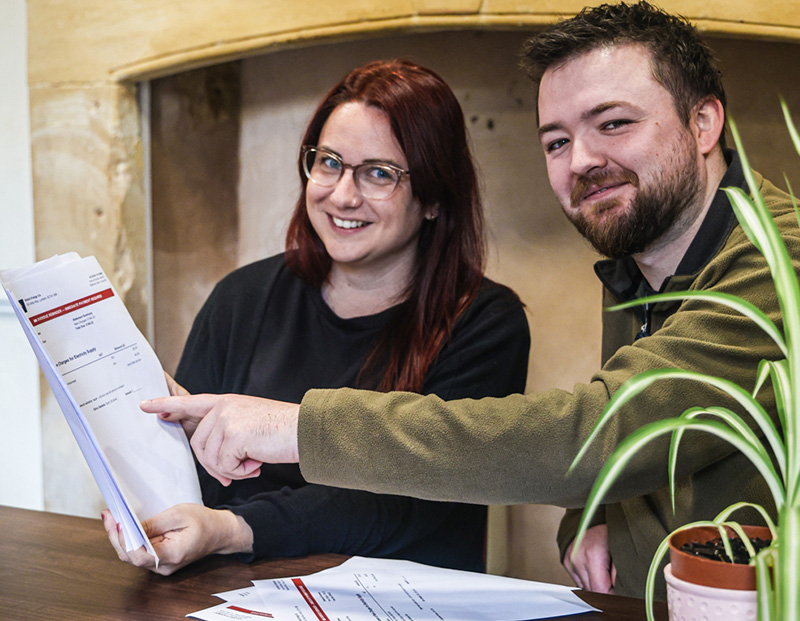 Emma Eccleston and Joshua Lee examining a stack of utitilty bills together
